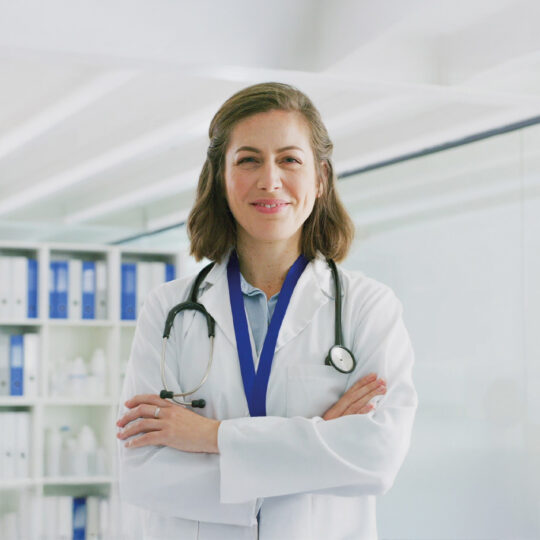 Lächelnde Frau mit weißen Arztkittel und Stethoskop